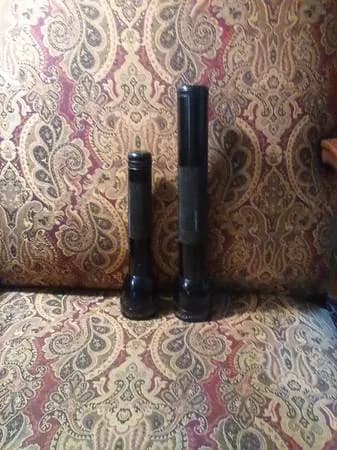 Phone photo of two flashlights on a paisley couch