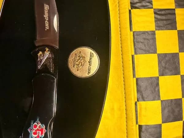 Phone photo of a folding knife and coin on a display piece