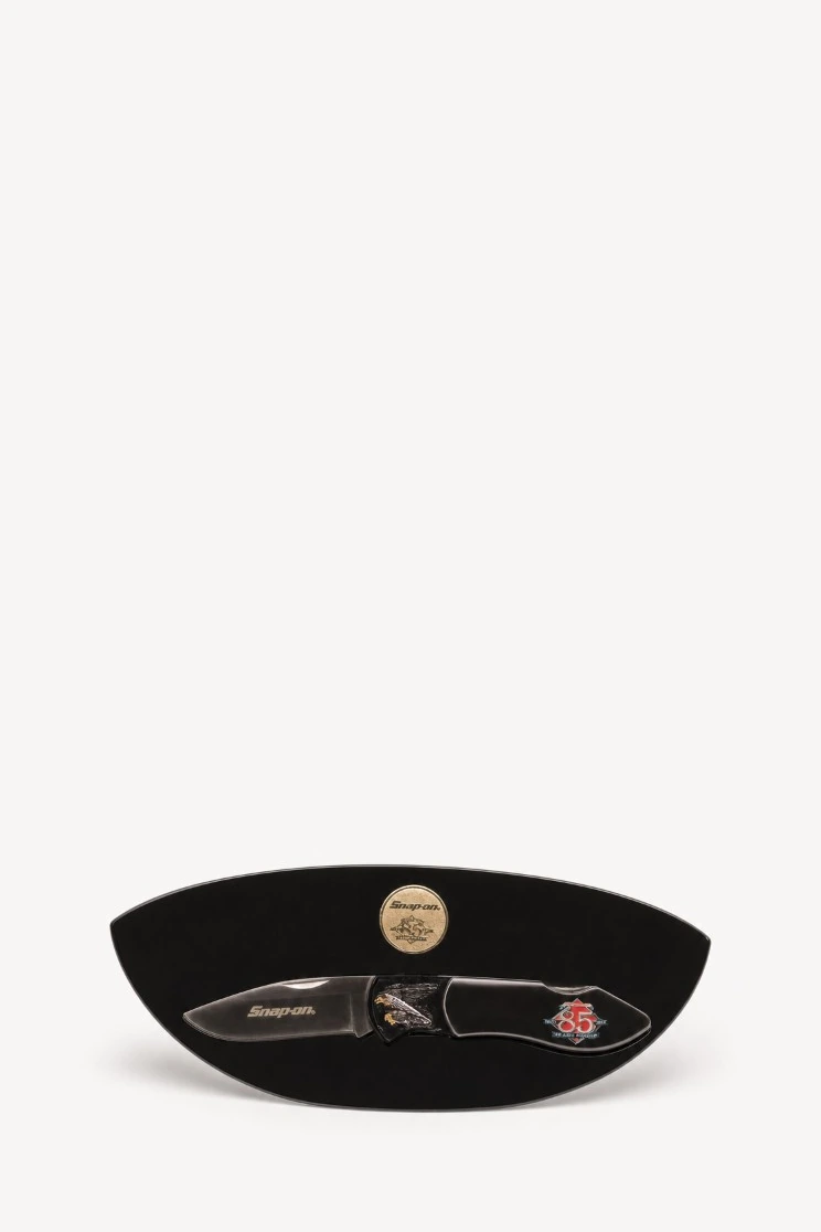 Studio listing photo of a folding knife and coin on white
